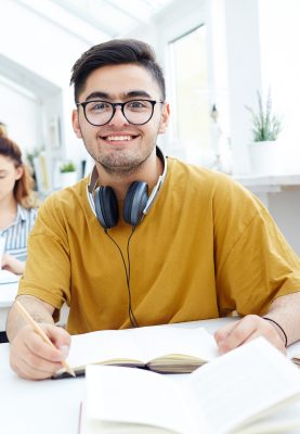 Happy guy with headphones preparing homework
